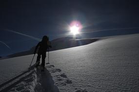 Back view of a person, skiing on the beautiful, snowy, white Alpine mountains in light