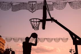 silhouette of a basketball player near the hoop