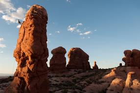 Beautiful landscape with the person, climbing on the rock in the Arches National Park in light, in Utah, USA