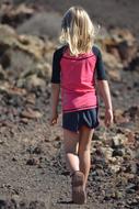 Back view of a blonde girl, hiking on the beautiful landscape with rocks