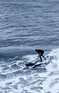 Person surfing on the beautiful, white wave in the blue ocean