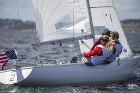 Women, sailing on the sailboat with the flag of USA, on the water
