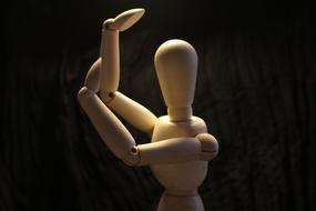 Wooden dummy, in light and shadow, at black background