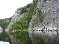 People on the catamarans, on the beautiful river, near the cliffs with the green and yellow trees, in Alloy