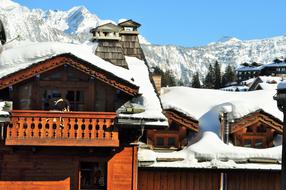 Beautiful, wooden chalets in snow, among the trees, near the mountains in Haute-Savoie, France