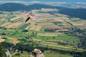 glider flies over green fields