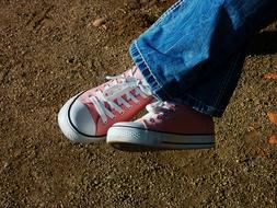 Red, white and black sneakers on the person with jeans