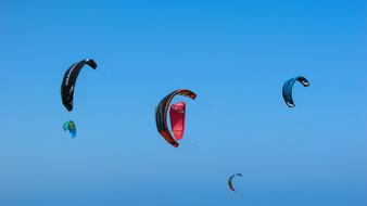 bright kitesurfing wings at blue sky