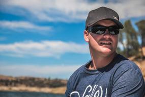Man in glasses and cap, in light, on the boat, among the beautiful lake, among the colorful plants