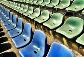 Shiny, blue and green bucket seats on the football stadium, in lig