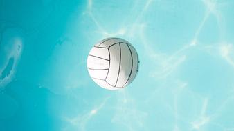 White and black volleyball, on the beautiful, turquoise water in light