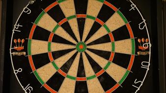 Close-up of the colorful dart board, with the numbers, on the black wall