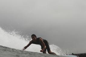 Person, surfing on the waves, on the water, under cloudy sky