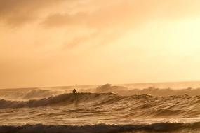 distant surfer on wave at Sunset sky