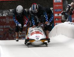 Team in colorful uniform on the bobsled competition with snow