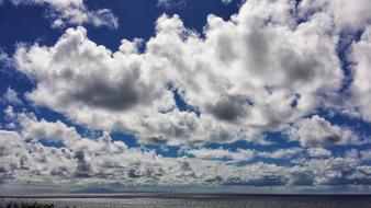 Beautiful, blue sky with clouds, above the shiny water with light