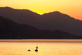 Boat on the water, near the beautiful mountains, at colorful, gradient sunrise, in Turkey