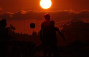 Silhouettes of the boys, playing football, in Acapulco, at beautiful sunset