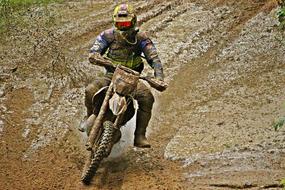Colorful person on the motocross Enduro competition, on the mud