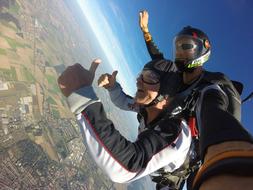 Tandem of the people, jumping on the parachute, above the colorful and beautiful landscape