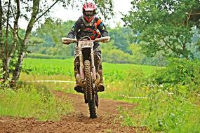 Person in colorful equipment on the dirtbike, among the colorful and beautiful plants, on the Enduro race