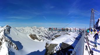 People on the beautiful, snowy mountains in SÃ¶lden, Austria, under the blue sky with clouds