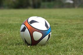 Colorful, gradient football ball, on the green grass field