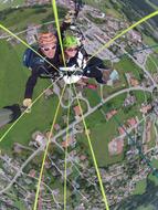 People, doing paragliding, above the beautiful landscape of Switzerland, with the houses, among the green plants