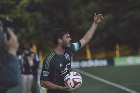 Soccer player, holding colorful ball, on the game, with the spectators
