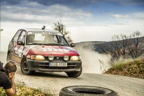 Person, taking photo of the colorful Rally car, on the road, among the colorful and beautiful hills