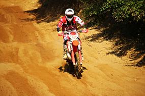 motorcyclist on a sandy road near the bushes
