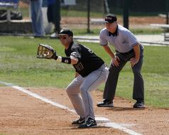 Baseball player at the first base, near the umpire, on the competition