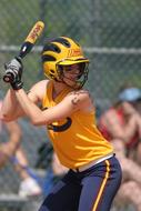 Softball female player in yellow and blue uniform, with the bat, on the competition in Texas