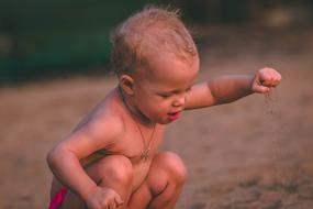 kid is playing with sand on the beach