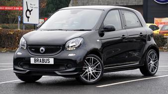 Shiny, black car with the "Brabus" sign, on the road, near the colorful cars