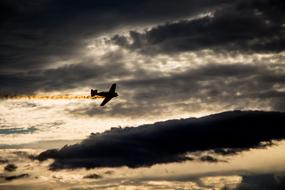 Silhouette of the airplane, in the colorful sky, with the sunset, with the clouds