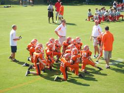 Young football players and other people, on the field, in light, on the game