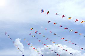 Bunting with the colorful flags, at blue sky with white clouds on background
