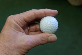 Golf Ball in hand on blurred background