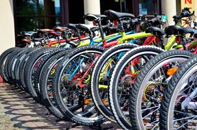 Colorful, shiny bicycles in the row, near the building