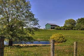 pond and green Barn behind wire fence