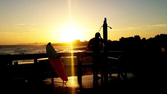 the surfer takes a shower on the ocean against the background of a golden sunset