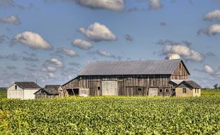 old barn in the middle of a green field