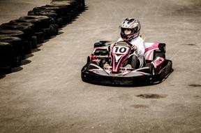 Person, in the colorful equipment, on the colorful gokart, on the track, among the tyres