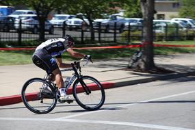 Biker, cycling on the bike, on the road, among the trees, near the cars, in light