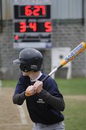 Junior baseball player, with the bat, near the score counter, on background