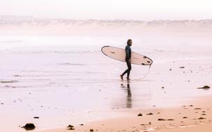 surfer with board on deserted ocean beach