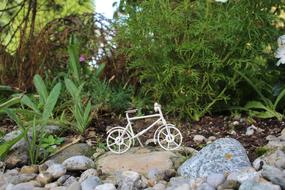 White bike on the rocks, among the beautiful, green plants