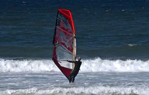 man on surfboard with sail on the sea