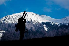 silhouette of a tourist with skis in the mountains